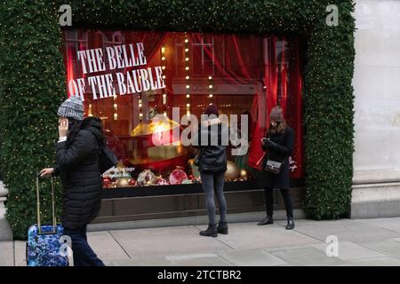 I turisti di Natale si divertono nei grandi magazzini di lusso Selfridges su Oxford Street, vetrina natalizia natalizia, nel centro di Londra, in Inghilterra, nel Regno Unito Foto Stock