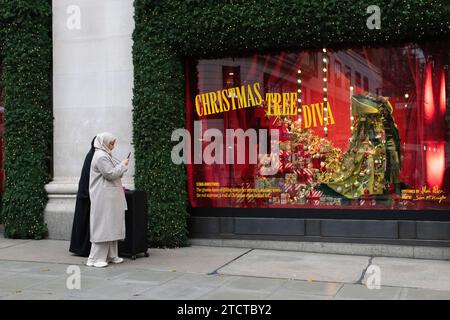 I turisti di Natale si divertono nei grandi magazzini di lusso Selfridges su Oxford Street, vetrina natalizia natalizia, nel centro di Londra, in Inghilterra, nel Regno Unito Foto Stock