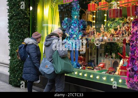 Christmas tourists enjoying Selfridges luxury department store on Oxford Street festive Christmas window display, central London, England, UK Stock Photo