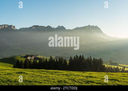 Paesaggio rurale nella regione dell'Appenzello con case coloniche e prati all'ultima luce del sole serale, vista sui monti Alpstein con Saentis Foto Stock