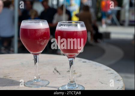 Famosa birra rossa lambic kriek, birra alla ciliegia fresca servita all'aperto nel festival belga della birra a Durbuy, speciale bicchiere di birra belga alle luci del sole, vicino a u Foto Stock