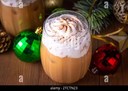 Bevanda al latte ghiacciato, gustosa bevanda natalizia di Capodanno cioccolata calda o cocktail di caffè con panna montata e sciroppo di pan di zenzero, con frusta Foto Stock