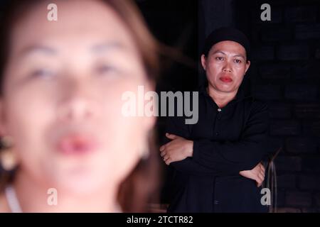 Ritratto ravvicinato di una donna triste con una giovane donna sorridente sfocata in primo piano. Foto Stock