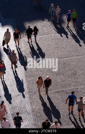 I turisti passeggiano in una piazza alla luce del sole, Roma, Italia Foto Stock