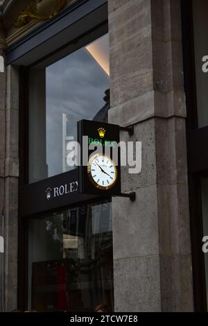 Cartello dell'orologio Rolex che indica l'ora e il logo Rolex fuori da un rivenditore ufficiale Rolex nella via dello shopping Meir nel centro di Anversa Foto Stock
