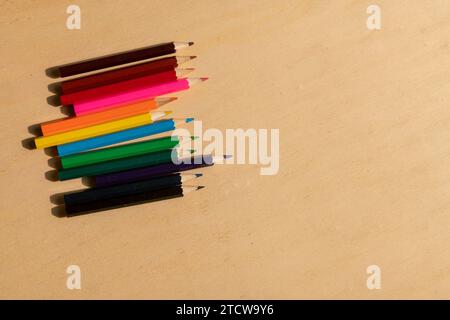 matite colorate: assortimento vivace disposto su un tavolo di legno, pronto a scatenare la creatività con la loro gamma di colori vivaci. Foto Stock