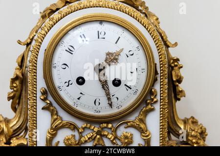 Orologio mantel vintage, foto ravvicinata, vista frontale. Quadrante bianco con numeri arabi e dettagli interni barocchi Foto Stock