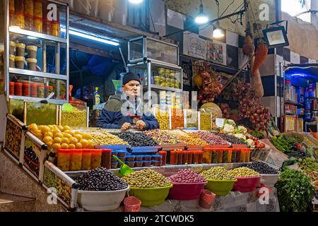 Venditore marocchino che vende olive da tavola al mercato alimentare della città di Meknes, Fez-Meknes, Marocco Foto Stock