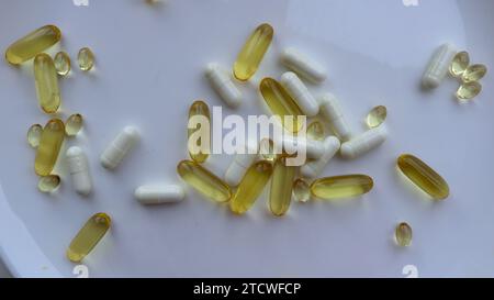 capsule diverse con vitamine su una piastra bianca vista ravvicinata dall'alto, sfondo sul tema dell'assunzione di farmaci e integratori alimentari Foto Stock