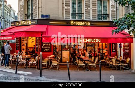 Gente che si gode un drink fuori le Chinon, una brasserie, un caffè in Rue des Abbesses a Montmartre, Parigi, Francia Foto Stock