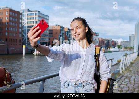 Giovane studentessa turista adolescente che scatta foto selfie su smartphone nella città portuale europea Foto Stock