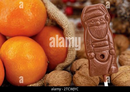 Primo piano di un regalo tradizionale per i bambini per St Giorno del Nicola il 6 dicembre con Babbo Natale al cioccolato, mandarini e noci Foto Stock