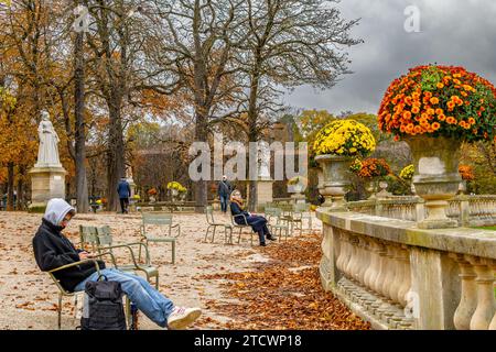 Persone sedute sulle sedie in una fredda giornata autunnale nel Jardin du Luxembourg, Parigi, Francia Foto Stock