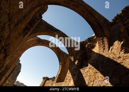 Antichi archi in pietra contro un cielo azzurro, rovine storiche con intricata architettura della città romana di Merida, Spagna Foto Stock