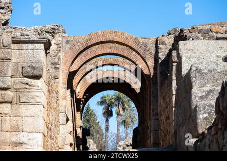 Antichi archi in pietra contro un cielo azzurro, rovine storiche con intricata architettura della città romana di Merida, Spagna Foto Stock