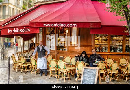 Un cameriere che si trova all'esterno di Les Philosophes, un ristorante francese, un bistro situato nell'area Marais di Parigi, Francia Foto Stock