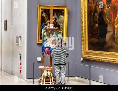 Un'artista donna che copia un dipinto in una galleria all'interno del Museo del Louvre a Parigi, in Francia Foto Stock