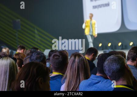 Vista angolare bassa dell'altoparlante maschio per presentazioni a una folla di persone diverse nella sala conferenze Foto Stock