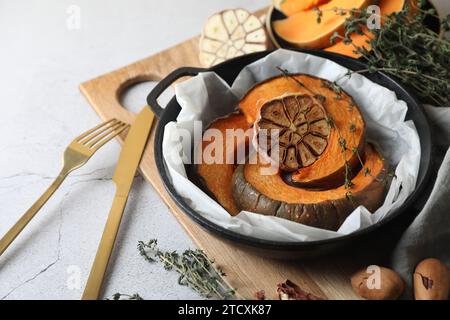 Fette di zucca appena sfornate con aglio e timo su un tavolo leggero, primo piano Foto Stock