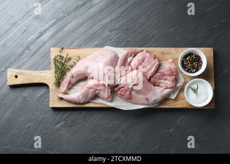 Carne fresca di coniglio crudo e spezie su tavolo nero, vista dall'alto Foto Stock