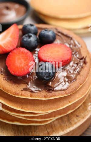 Pancake gustosi con pasta al cioccolato e frutti di bosco sul tavolo, primo piano Foto Stock