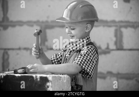 Bambino in casco protettivo arancione con strumenti per la ristrutturazione. Riparazione a casa. Foto Stock