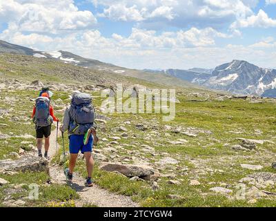 Gli escursionisti con zaini attraversano l'aspra distesa del North Inlet Trail, ammirando le ampie vedute del Parco Nazionale delle Montagne Rocciose. Foto Stock