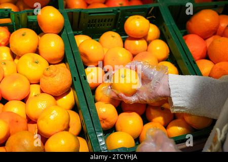 Vista ravvicinata di una donna irriconoscibile che raccoglie arance in un negozio di alimentari, punto di vista personale. Foto Stock