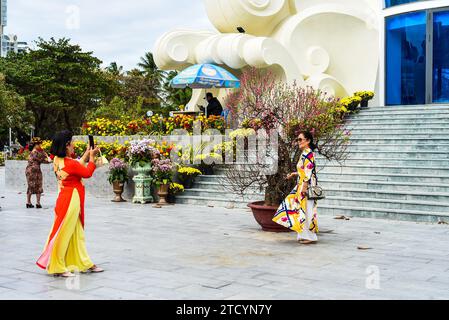 Nha Trang, Vietnam - 13 gennaio 2023 donne vietnamite in costumi tradizionali in posa per foto contro molte decorazioni nella piazza di Nha Trang Foto Stock