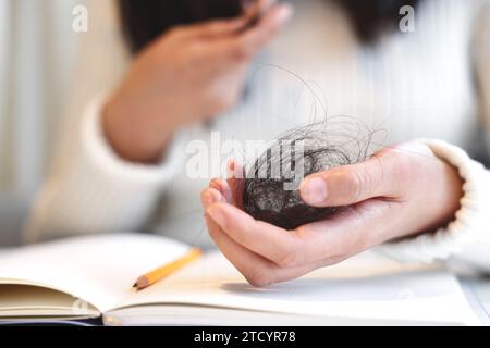 Una donna affetta da alopecia tiene i capelli nelle mani Foto Stock