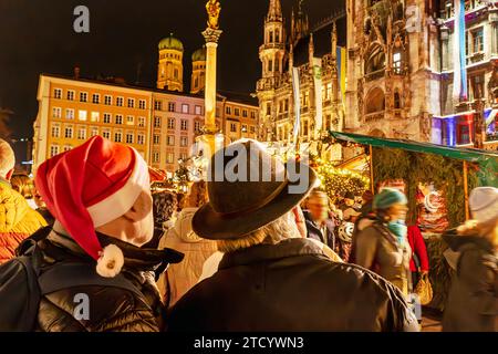 Viele Münchner und Touristen bummeln abends über den Christkindlmarkt am Marienplatz, München, Dezember 2023 Deutschland, München, 14. Dicembre 2023, viele Münchner und Touristen bummeln abends über den Christkindlmarkt am Marienplatz, suchen Weihnachtsgeschenke, machen Weihnachtseinkäufe, Besucher mit Nikolausmütze, festlicher Lichterglanz, Winterwetter bei 7 Grad Plus, Donnerstagabend, Geschäfte, Adventszeit, Weihnachtszeit, Wirtschaft, Winter, Bayern, *** molti residenti e turisti di Monaco passeggiano per il mercatino di Natale in Marienplatz la sera, Monaco, dicembre 2023 Germania, Muni Foto Stock