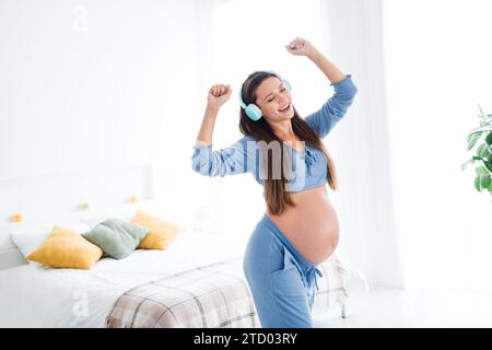 Foto di felicissima felice positiva bella incinta futura mamma che balla da sola godendo di una stanza di luce bianca di buon umore all'interno Foto Stock