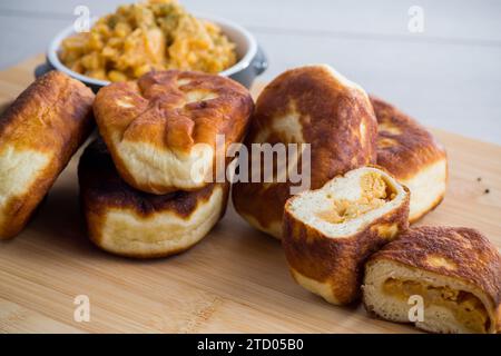 Torte di quaresima fritte ripiene di piselli cotti all'interno, su un tavolo di legno. Cibo ucraino. Foto Stock