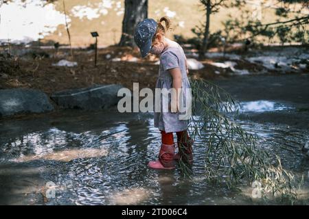 Bambino che gioca in una pozzanghera fangosa in una giornata bagnata Foto Stock