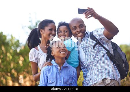 Famiglia nera felice, selfie e foto in natura per escursioni, collegamenti o fotografie all'aperto insieme. Madre africana, figli e padre sorridono Foto Stock