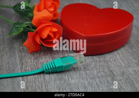 cuore rosso e rose rosse con cavo internet verde, immagine simbolica dell'amore online Foto Stock