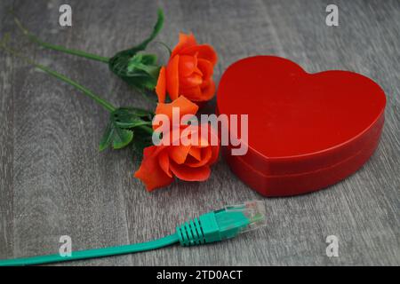 cuore rosso e rose rosse con cavo internet verde, immagine simbolica dell'amore online Foto Stock