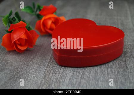 rose rosse artificiali con un portagioie rosso a forma di cuore Foto Stock