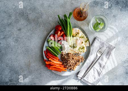 Un piatto ben equilibrato per la colazione che include pomodori ciliegini, cetrioli, cipolle verdi e peperoni rossi, accompagnato da cremoso formaggio feta e abbondante bo Foto Stock