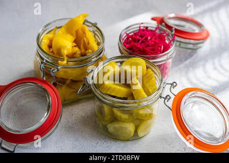 Tre vasetti di vetro pieni di vivaci verdure fermentate, tra cui peperoni caldi gialli, cavolo rosso con barbabietola e cetrioli sottaceto verdi, dispensare Foto Stock