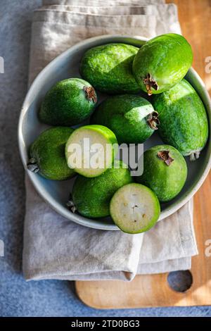 Collezione di feijoa maturi su una superficie di legno, con un panno rustico, che mostra l'intera sezione trasversale della feijoa verde. Foto Stock