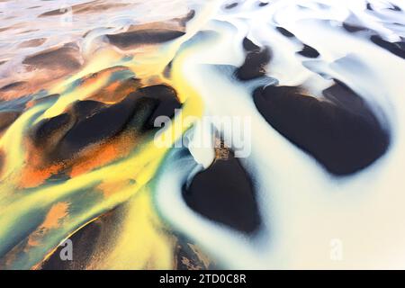 Un'immagine aerea che cattura i vivaci e astratti schemi di un bacino fluviale islandese con colori intersecanti Foto Stock