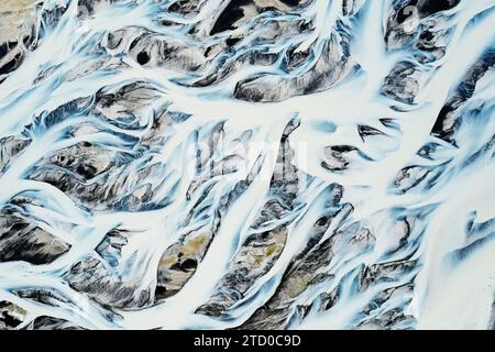 Un'istantanea aerea che cattura gli intricati schemi dei bacini fluviali in mezzo al paesaggio contrastante dell'Islanda Foto Stock