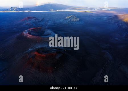 Una ripresa aerea cattura le consistenze e i colori drammatici del terreno vulcanico dell'Islanda, con formazioni rocciose e sfumature sottili sotto un vasto cielo Foto Stock