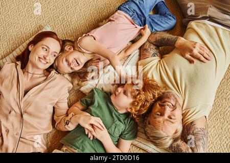 vista dall'alto di genitori felici e bambini sdraiati e al piano e che si divertono in un soggiorno moderno Foto Stock