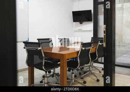 Interno della sala conferenze con sedie disposte intorno a un tavolo in legno in un ufficio vuoto e creativo visto attraverso la porta Foto Stock