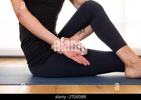 Una vista ravvicinata delle mani di un praticante di yoga mentre esegue un mudra seduto su un tappetino yoga, illustrando concentrazione e tranquillità. Foto Stock