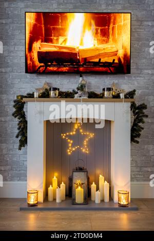 Caminetto, vestito per Natale con ghirlanda, stella e candele e un fuoco in tv Foto Stock