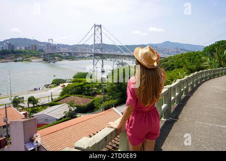 Vacanze a Santa Catarina. Vista posteriore della bellissima ragazza di moda che si gode la vista del ponte Hercilio Luz a Florianopolis, Brasile. Vacanze estive a Braz Foto Stock