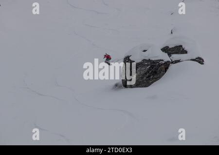 Vista dall'alto di uno snowboarder senza paura che salta sopra la formazione rocciosa su un paesaggio innevato durante le vacanze invernali in Canada Foto Stock